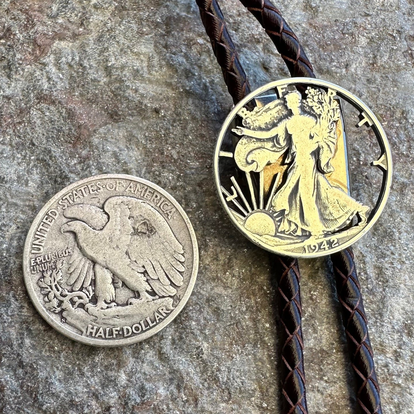U.S. Walking Liberty Half Dollar Hand Cut Silver Coin Bolo Tie with coin back to left on a grey rock surface. - Mountainstruck Coin Jewelry