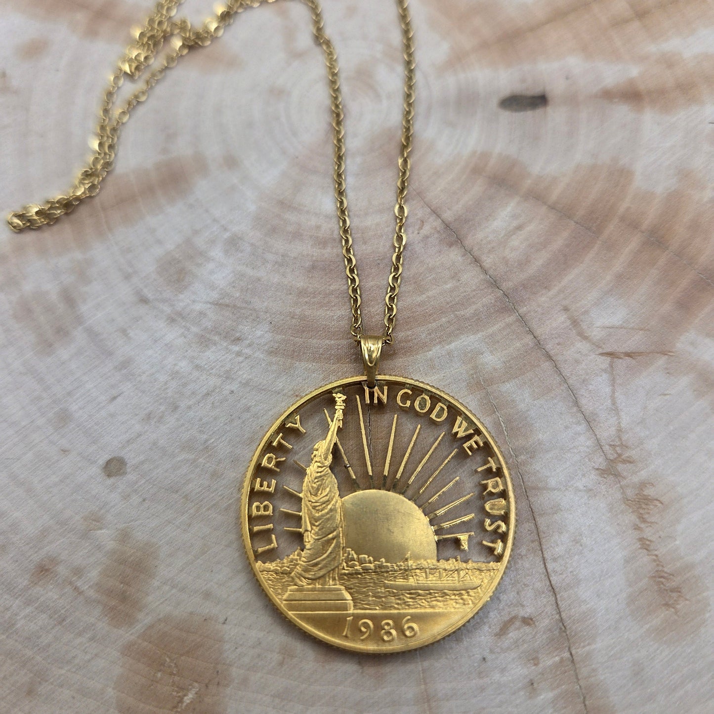 24k Plate Nation of Immigrants Cut Half Dollar Coin Necklace on a wood background. - Mountainstruck Coin Jewelry