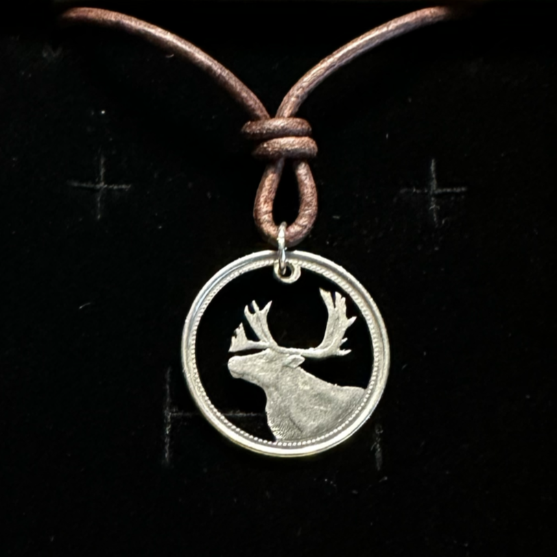 Canada Caribou 25 Cents hand cut coin necklace with a leather chain in a brown kraft box on a black velvet background. - Mountainstruck Coin Jewelry