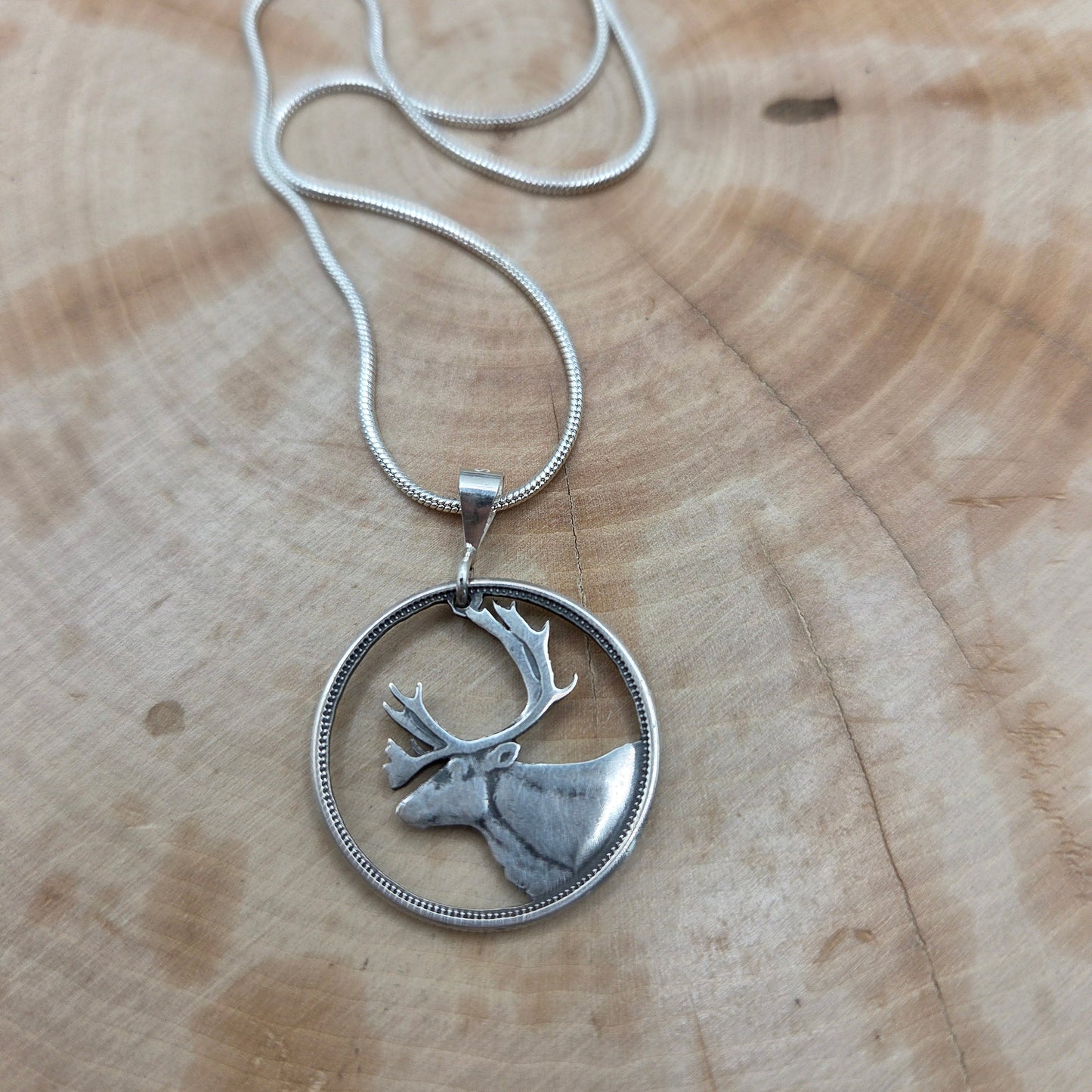Canada Caribou 25 Cents hand cut coin necklace with a snake chain on a wood background. - Mountainstruck Coin Jewelry