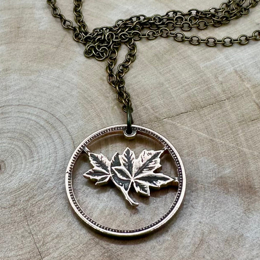 Canada Maple Leaf Penny Hand Cut Coin Necklace with bronze chain on a light wood round. - Mountainstruck Coin Jewelry