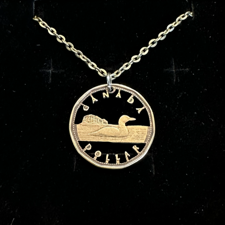 Canadian Loonie 1 Dollar Hand Cut Coin Necklace with stainless chain on a black velvet background. - Mountainstruck Coin Jewelry