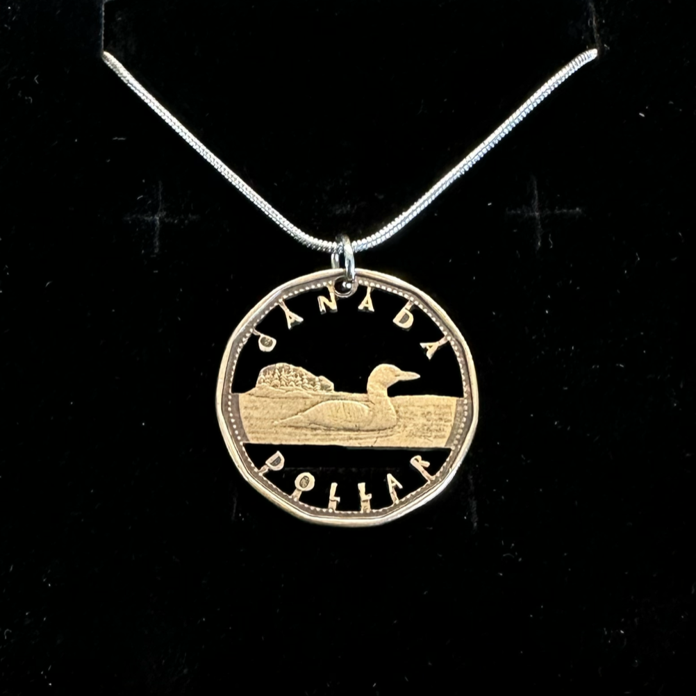 Canadian Loonie 1 Dollar Hand Cut Coin Necklace with a snake chain on a black velvet background. - Mountainstruck Coin Jewelry