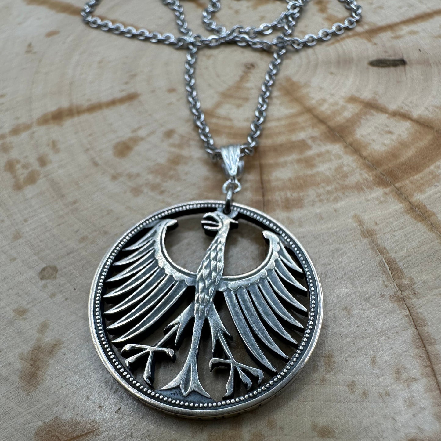 Germany Silver Eagle 5 Mark Hand Cut Coin Necklace on wood background. - Mountainstruck Coin Jewelry