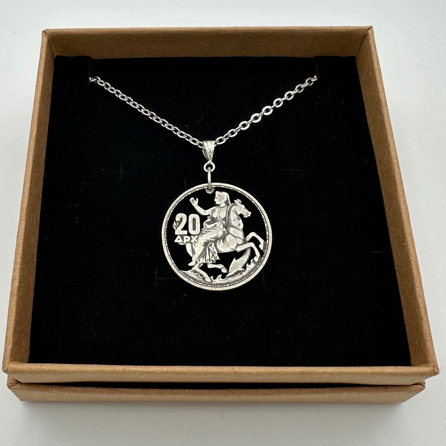 Greek Silver 20 Drachmai Hand Cut Coin Necklace in a brown kraft box on a black velvet background. - Mountainstruck Coin Jewelry