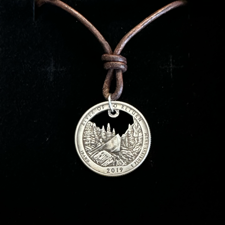 Idaho "River of No Return" Hand Cut Quarter Necklace with a leather cord in a brown kraft box on a black velvet background. - Mountainstruck Coin Jewelry