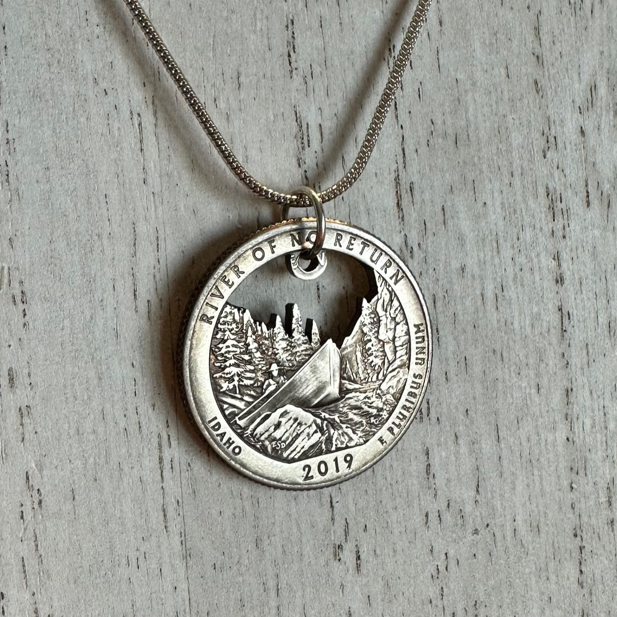 Idaho "River of No Return" Hand Cut Quarter Necklace with a snake chain on a white wood background. - Mountainstruck Coin Jewelry