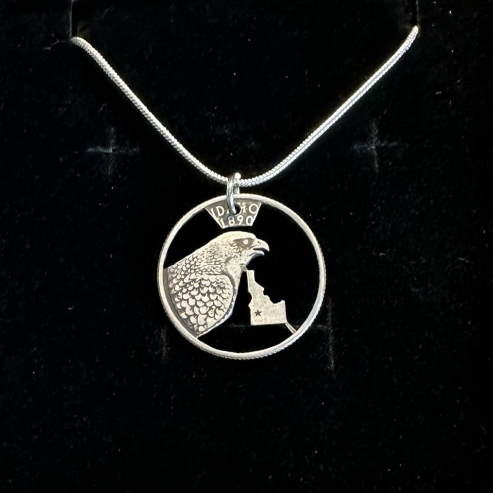 Idaho State Quarter Hand Cut Coin Necklace with a snake chain on a black velvet background. - Mountainstruck Coin Jewelry