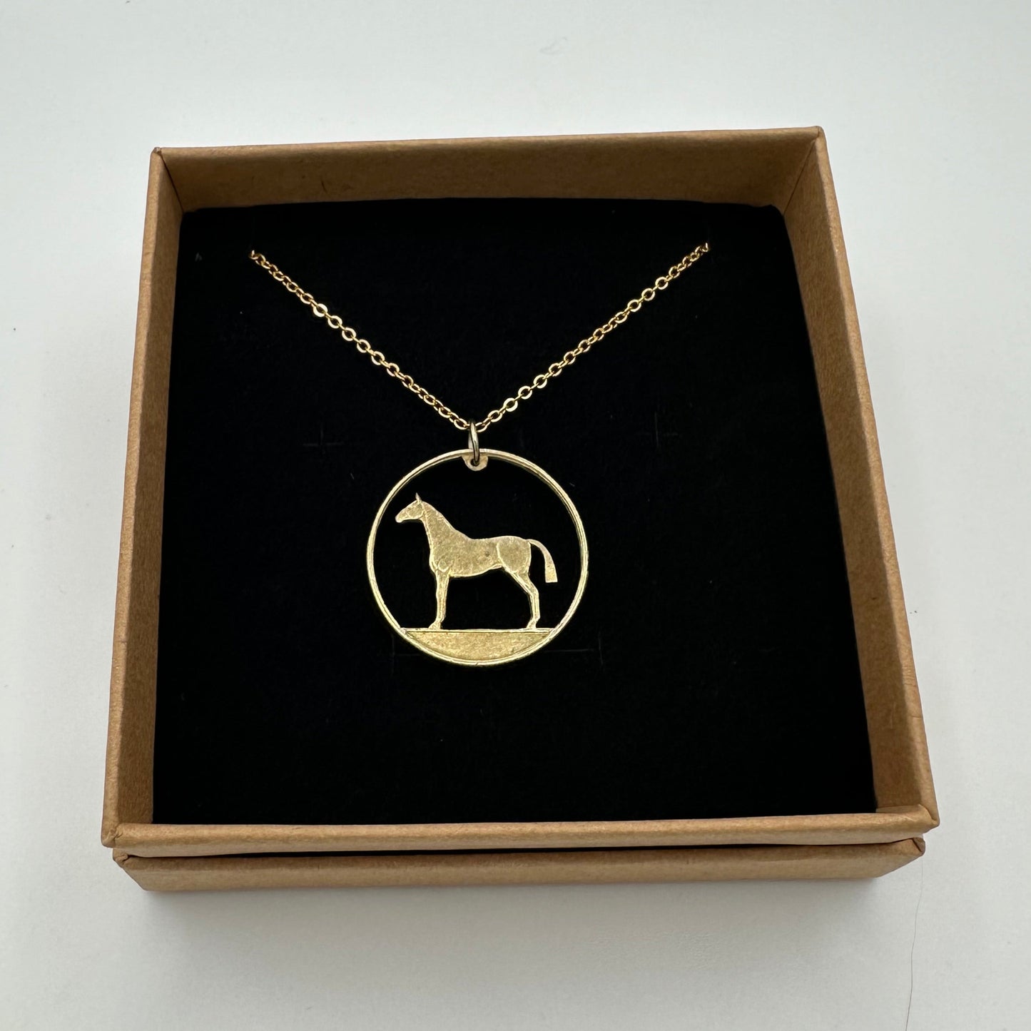 Ireland Horse 20 Pence Hand Cut Coin Necklace in a brown kraft box on a black velvet background. - Mountainstruck Coin Jewelry