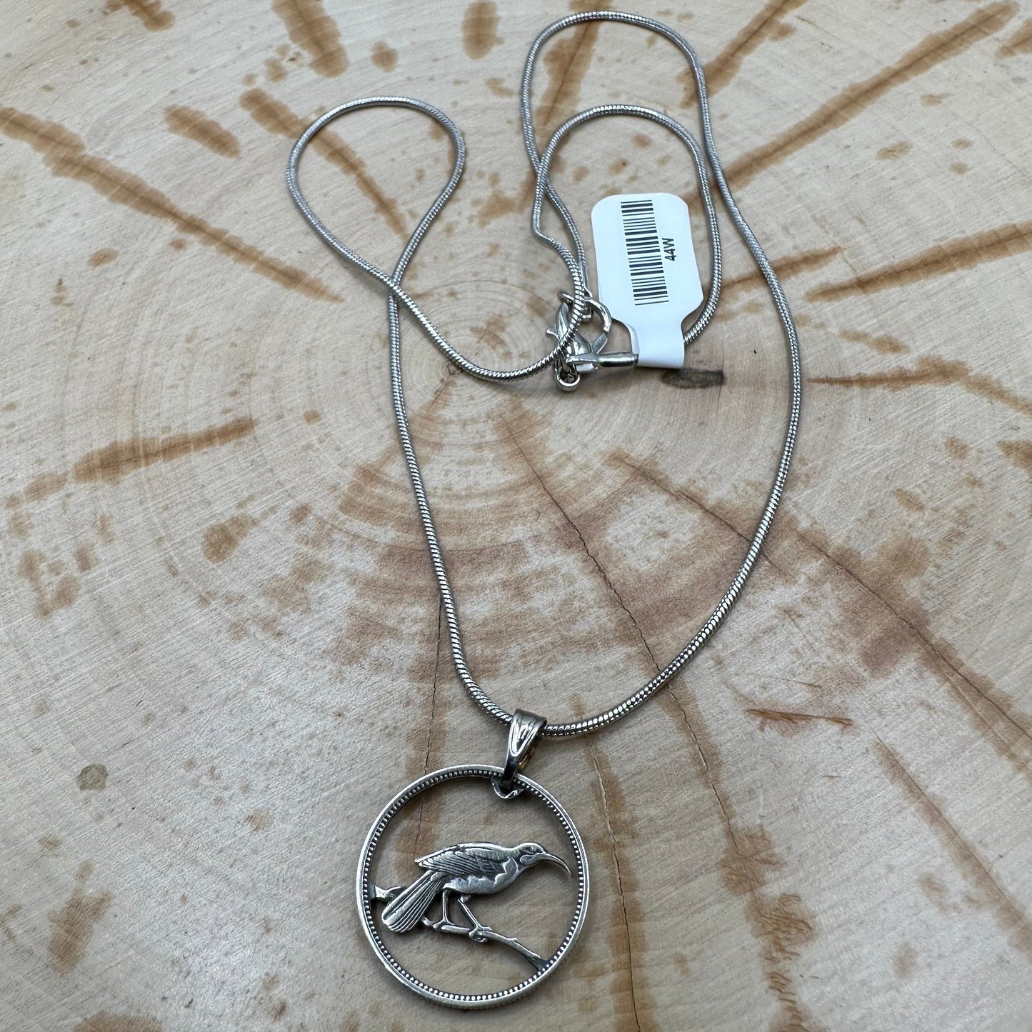 New Zealand Huia Bird 6 Pence Silver Hand Cut Coin Necklace on a black velvet background. - Mountainstruck Coin Jewelry