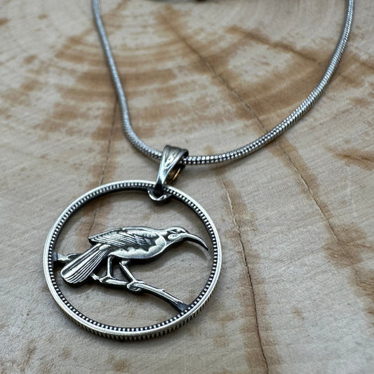 New Zealand Huia Bird 6 Pence Silver Hand Cut Coin Necklace on a black velvet background. - Mountainstruck Coin Jewelry