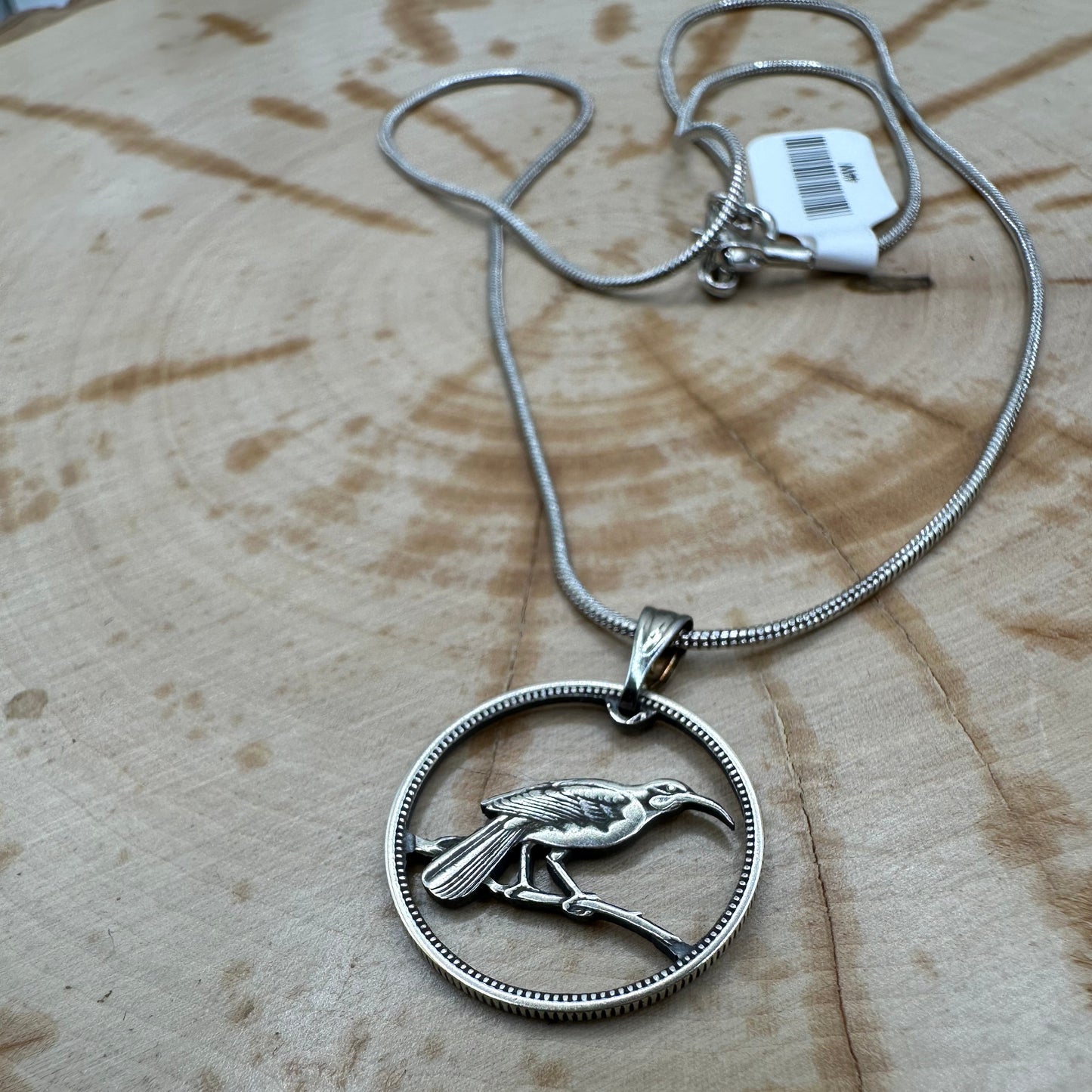 Huia Bird Silver New Zealand 6 Pence Hand Cut Coin Necklace on a black velvet background. - Mountainstruck Coin Jewelry