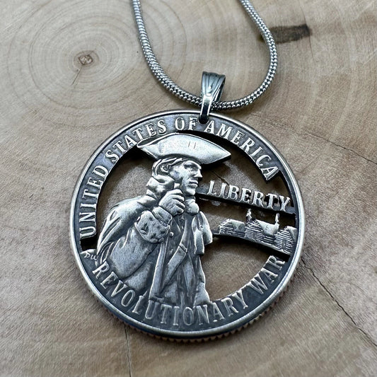 U.S. 2026 "Revolutionary War" Quarter Hand Cut Coin Necklace with a snake chain on a wood background. - Mountainstruck Coin Jewelry