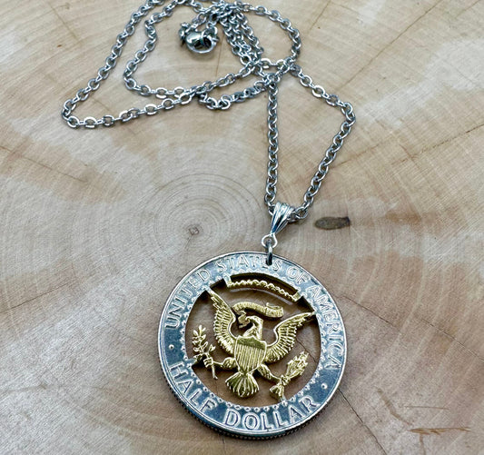 U.S. JFK Eagle Half Dollar Hand Cut Silver Coin Necklace with a 24k gold plated Eagle on a light wood background. - Mountainstruck Coin Jewelry