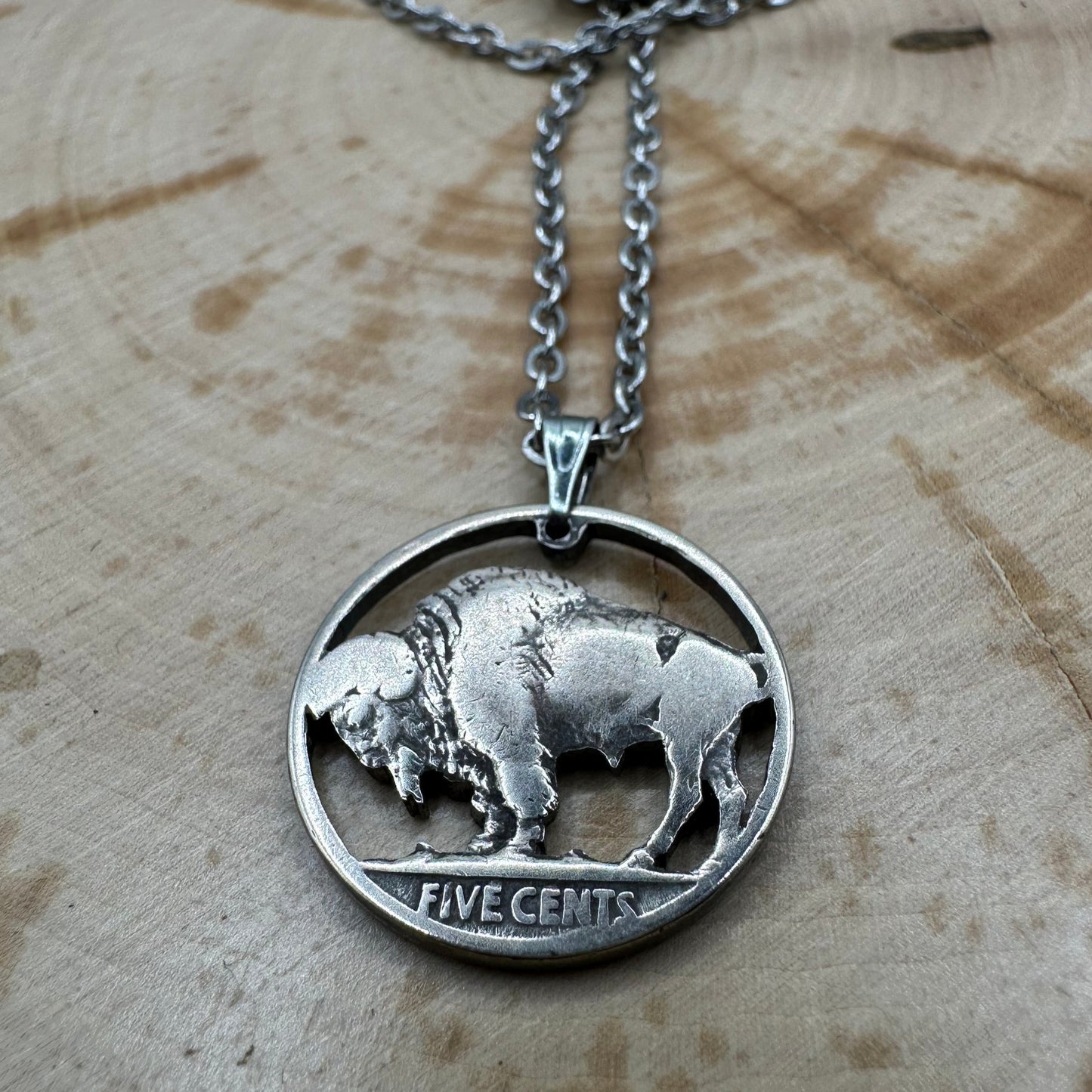 U.S. Buffalo Nickel Hand Cut Coin Necklace (Back) with a stainless chain on a wood background. - Mountainstruck Coin Jewelry