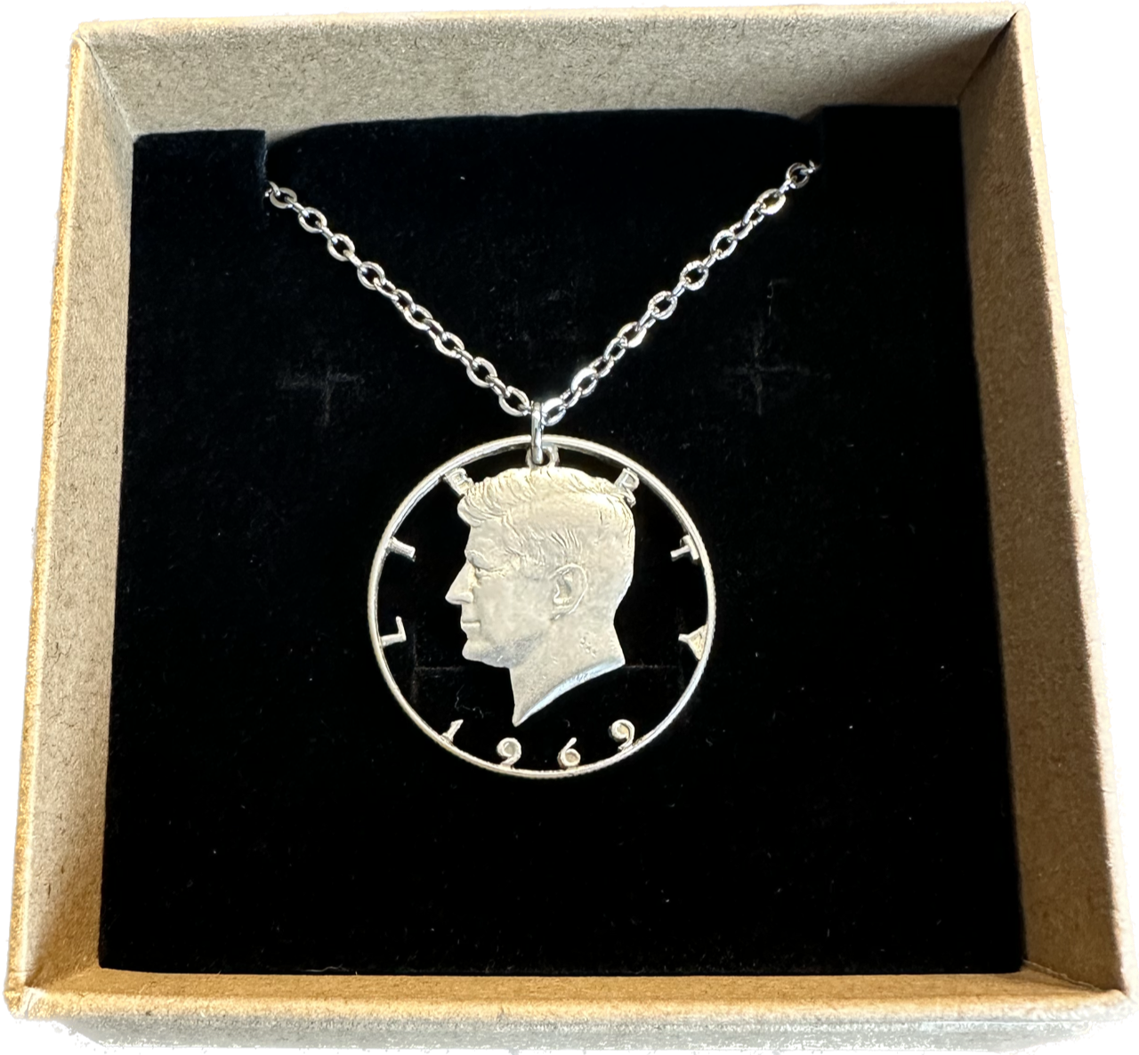U.S. JFK Half Dollar Hand Cut Silver Coin Necklace with stainless chain in a brown kraft box on black velvet background. - Mountainstruck Coin Jewelry