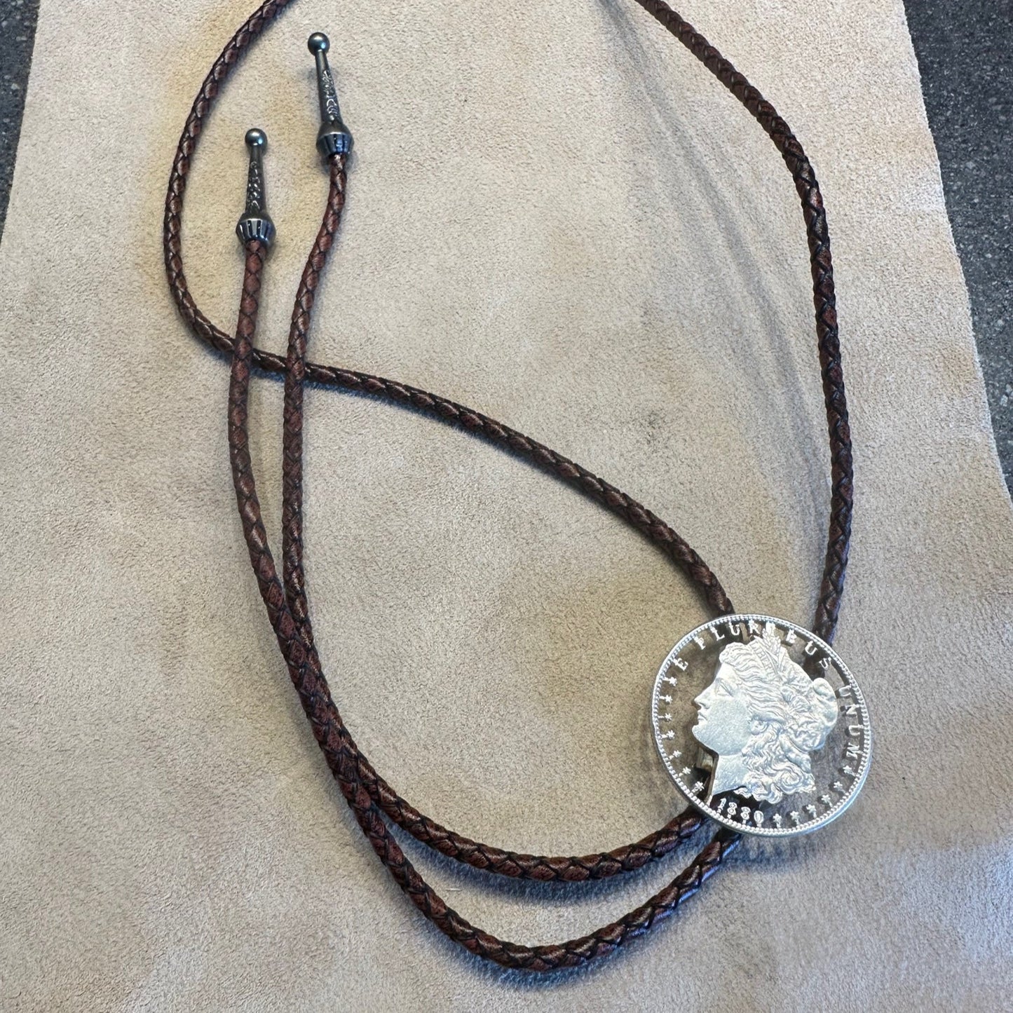 U.S. Morgan Hand Cut Silver Dollar Coin Bolo Tie (front) on light cloth background. - Mountainstruck Coin Jewelry