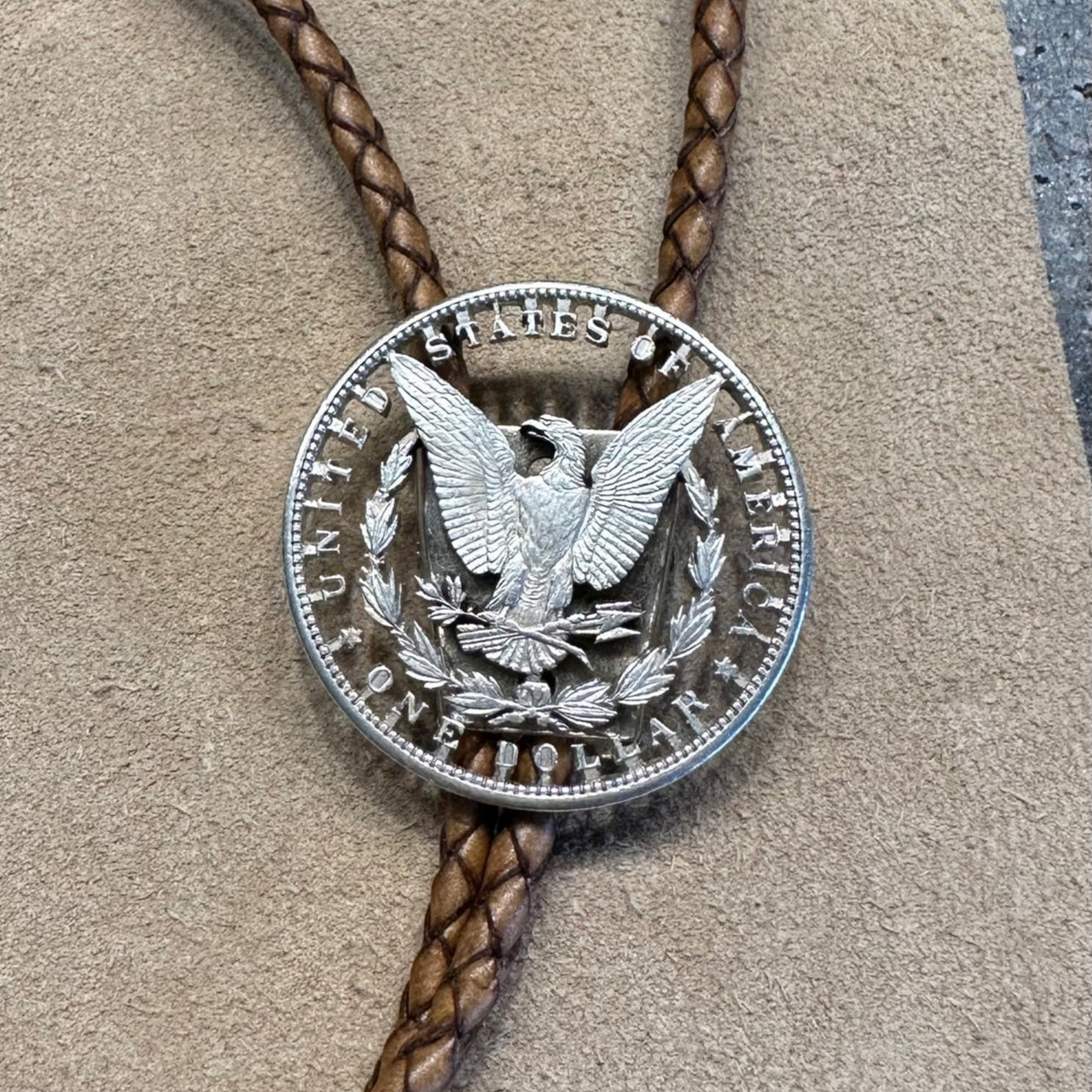 U.S. Morgan Hand Cut Silver Dollar Coin Bolo Tie (reverse) close up on light cloth background. - Mountainstruck Coin Jewelry