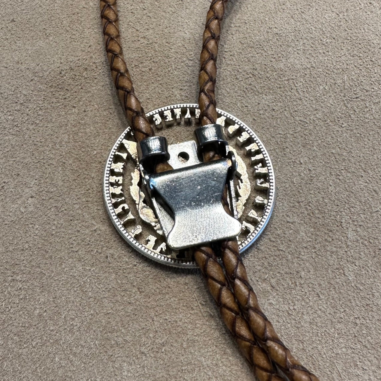 U.S. Morgan Hand Cut Silver Dollar Coin Bolo Tie (reverse) close up on clasp on light cloth background. - Mountainstruck Coin Jewelry