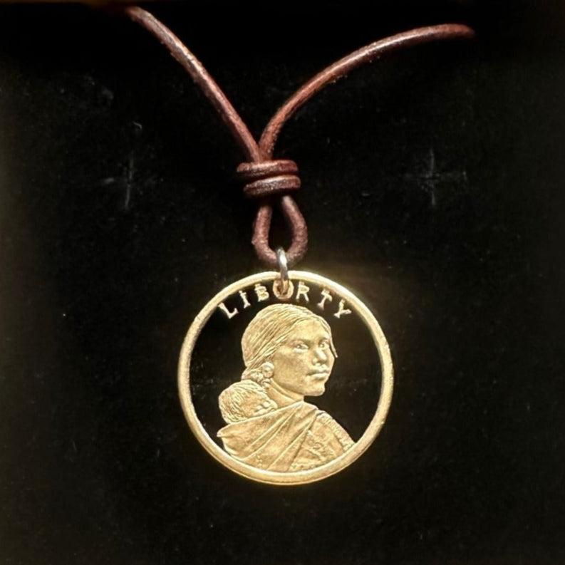 U.S. Sacagawea 1 Dollar Hand Cut Coin Necklace with leather cord in a brown kraft box on a black velvet background. - Mountainstruck Coin Jewelry
