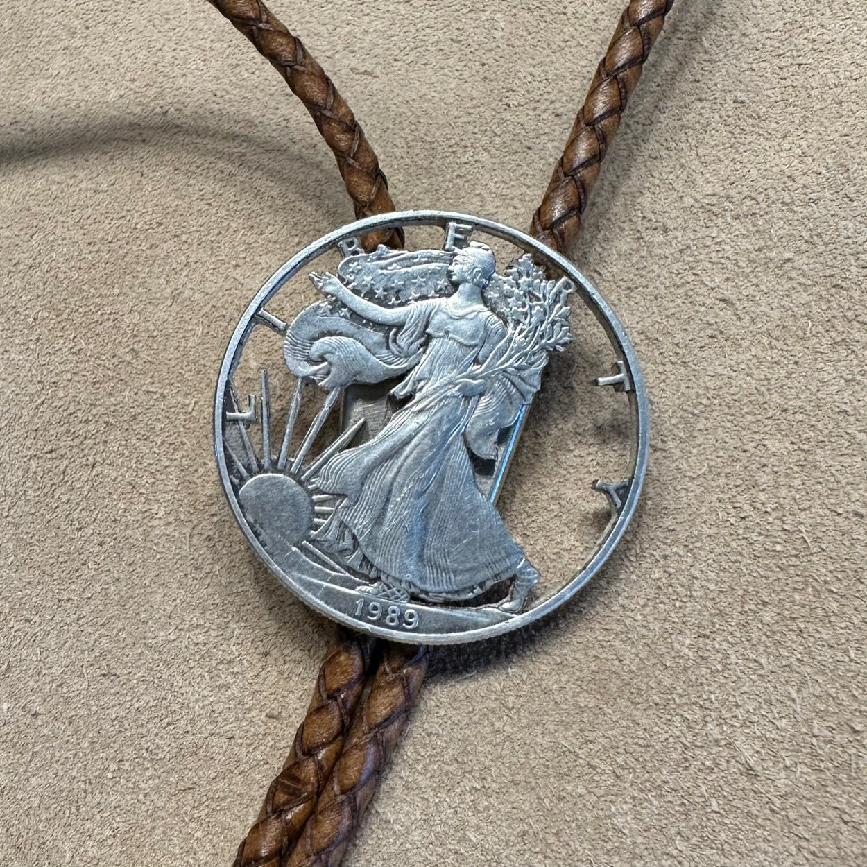 U.S. Silver Eagle Hand Cut Coin Bolo Tie close up on a light cloth background. - Mountainstruck Coin Jewelry