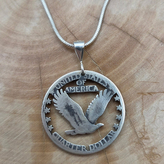U.S. Soaring Eagle Quarter Hand Cut Silver Coin Necklace on a wood background. - Mountainstruck Coin Jewelry