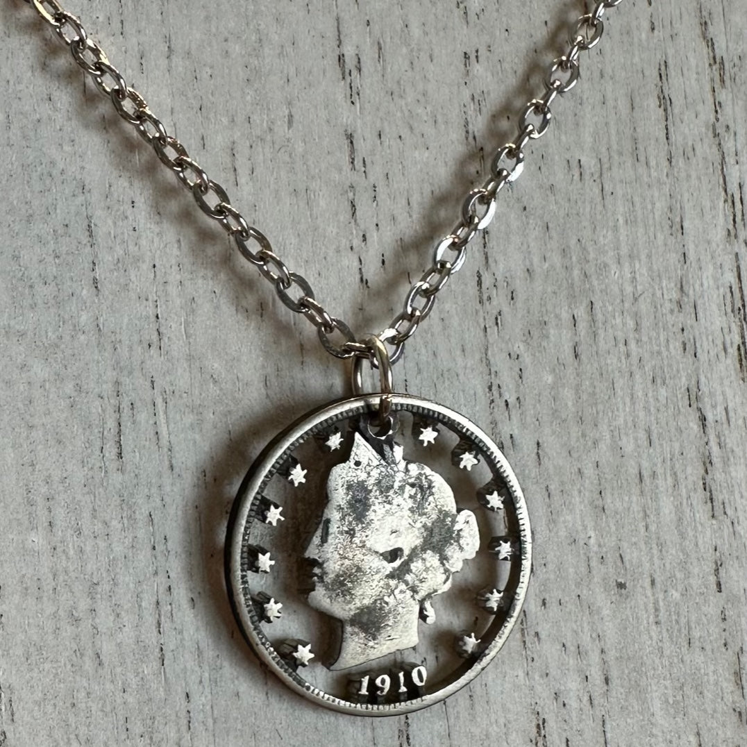 U.S. "V" Nickel Hand Cut Coin Necklace with a stainless chain on a white wood background. - Mountainstruck Coin Jewelry