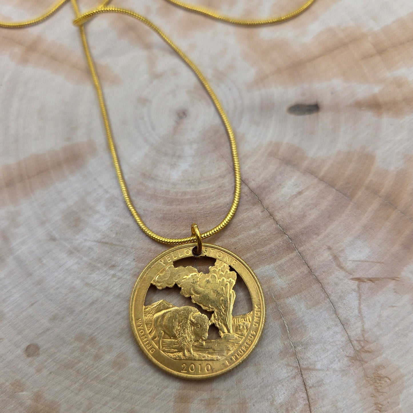 U.S. Yellowstone National Park Quarter Hand Cut Coin Necklace 24k gold plated on a wood background. - Mountainstruck Coin Jewelry