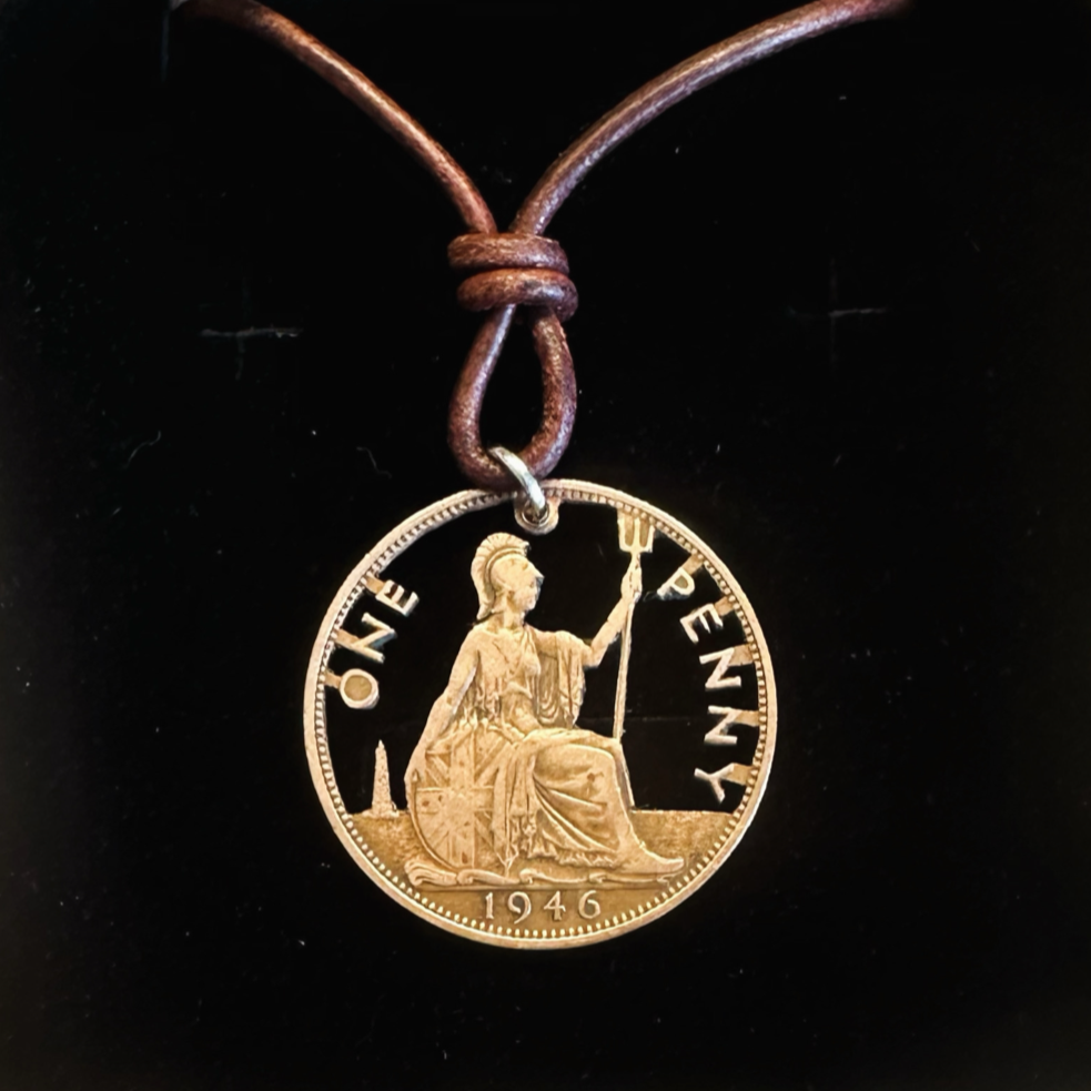 UK One Penny Hand Cut Coin Necklace with a leather cord in a brown kraft box on a black velvet background. - Mountainstruck Coin Jewelry
