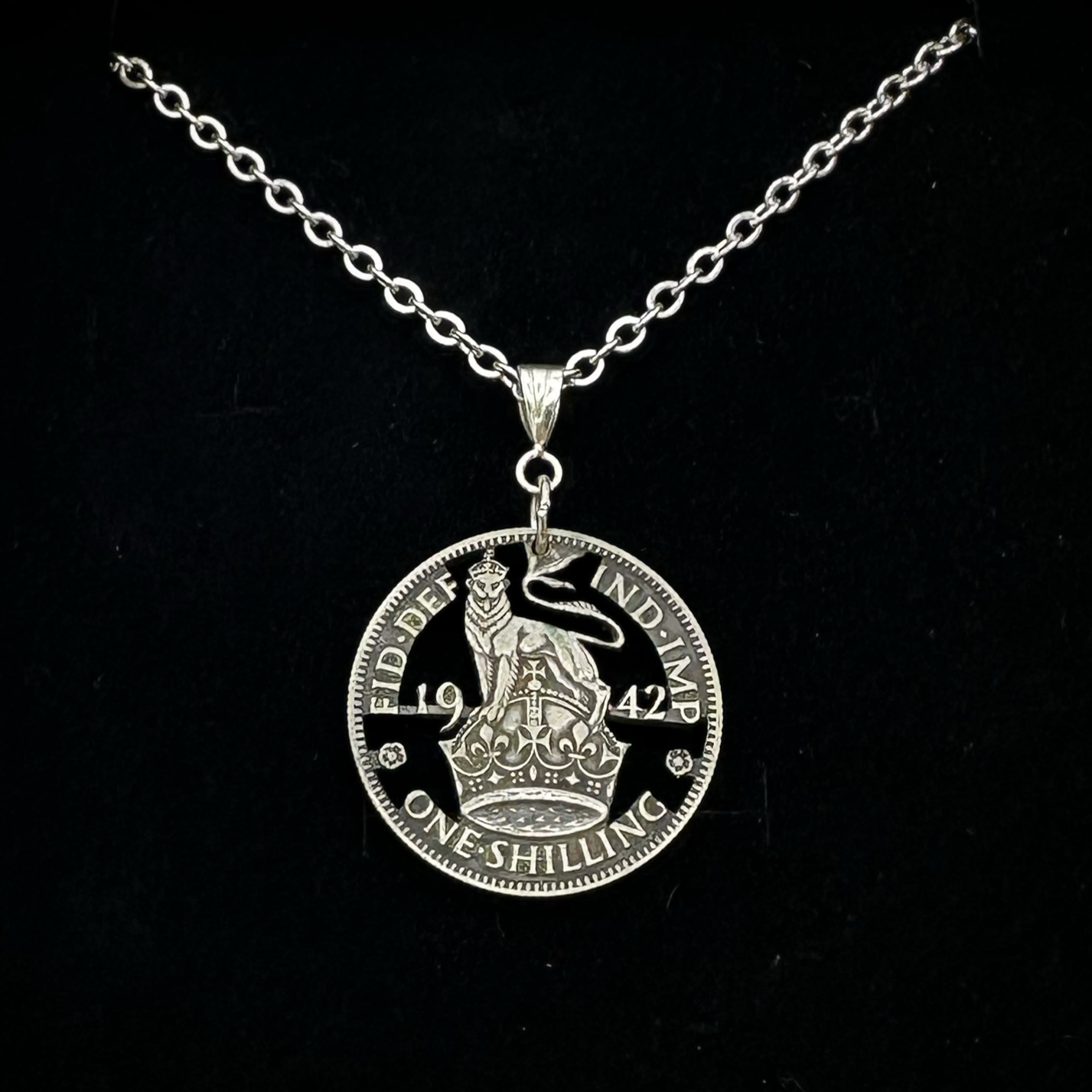UK One Shilling Hand Cut Silver Coin Necklace with stainless chain on a black velvet background. - Mountainstruck Coin Jewelry