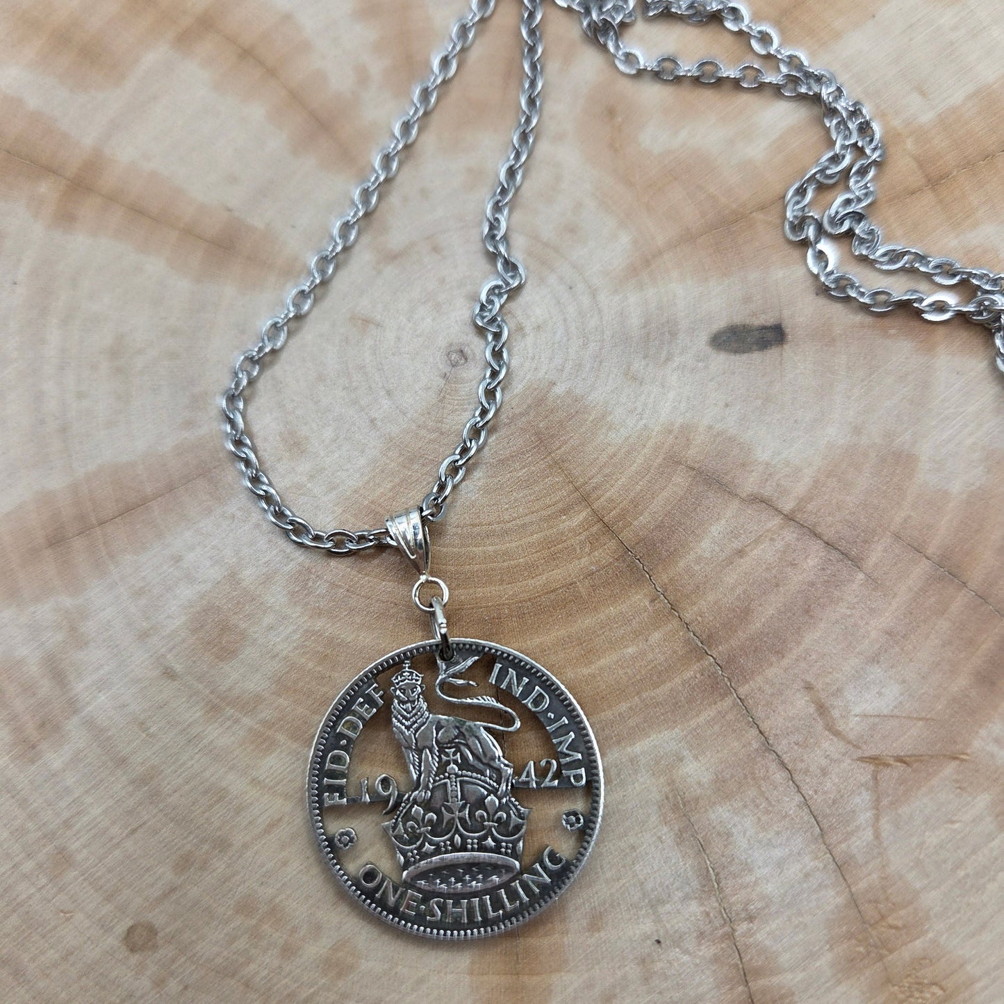 UK One Shilling Hand Cut Silver Coin Necklace with stainless chain on a wood background. - Mountainstruck Coin Jewelry