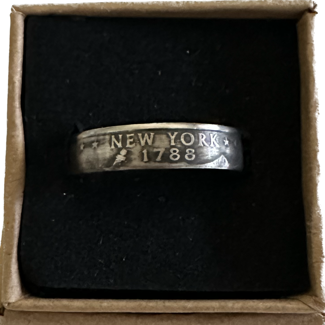 U.S. State Quarter Coin Ring featuring New York in a brown kraft box on a black velvet background. - Mountainstruck Coin Jewelry