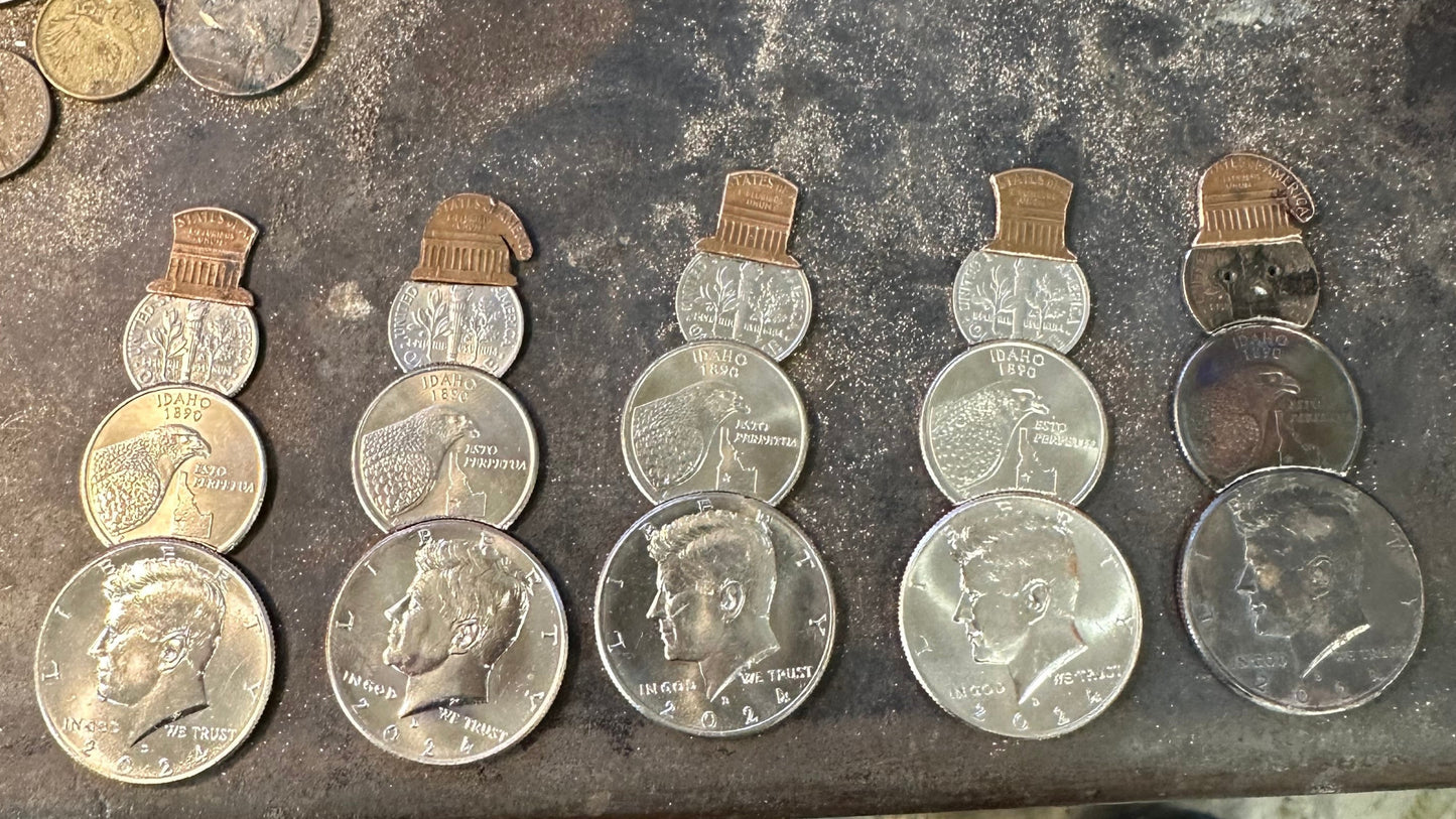 2024 Snowman Coin Christmas Ornament with a selection of U.S. coins (penny, dime, Idaho Quarter, and 2024 uncirculated half dollar) soldered into a snowman with a red ribbon scarf and golden tassel on a metal background. - Mountainstruck Coin Jewelry