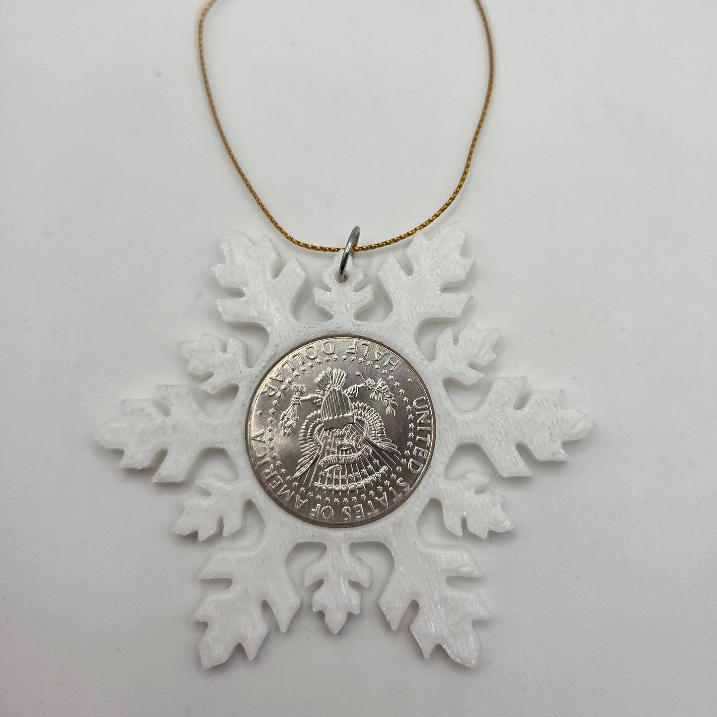 2025 Half Dollar Christmas Ornament with an uncirculated half dollar cased inside a white 3D printed snowflake with golden tassel on a white background. - Mountainstruck Coin Jewelry