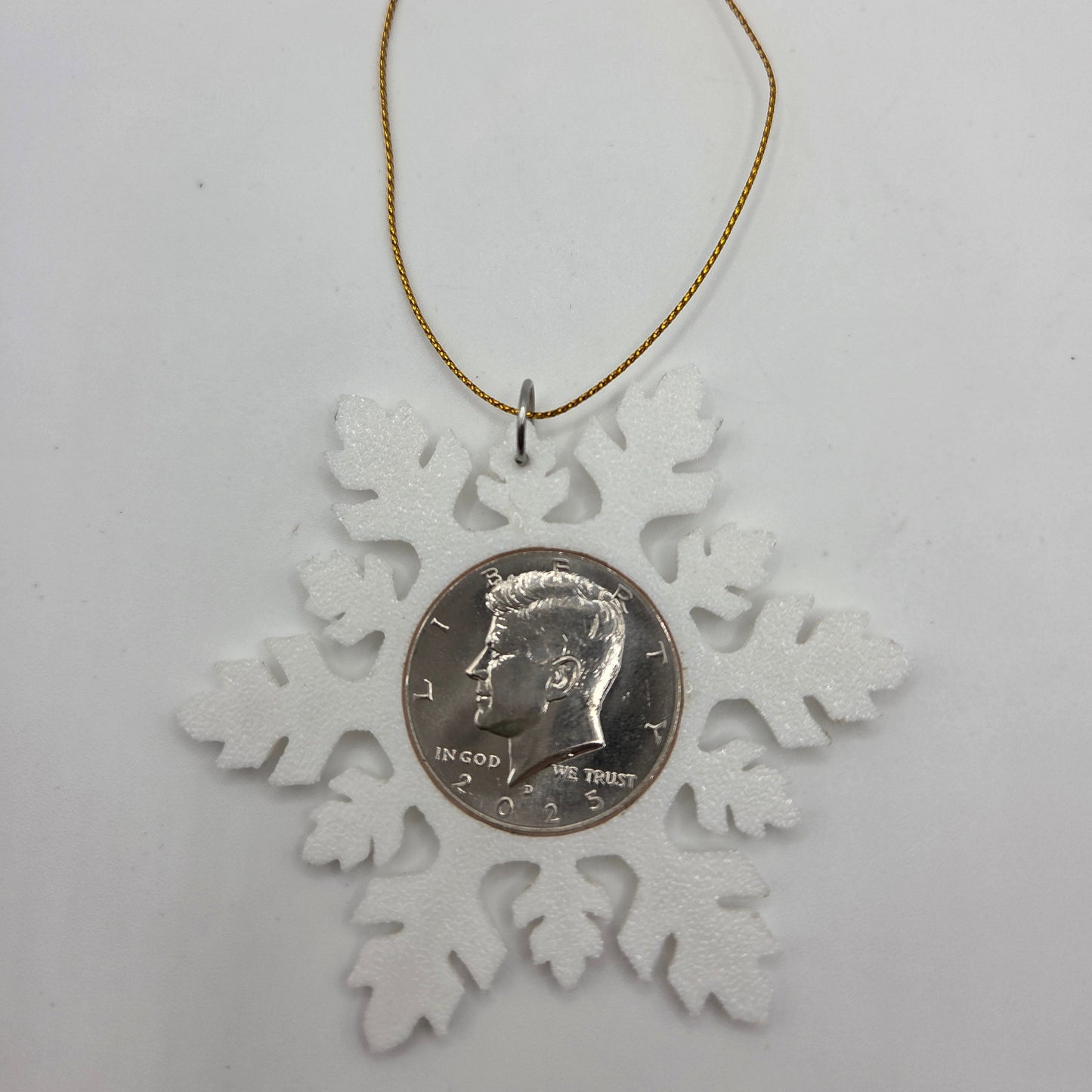 2025 Half Dollar Christmas Ornament with an uncirculated half dollar cased inside a white 3D printed snowflake with golden tassel on a white background. - Mountainstruck Coin Jewelry