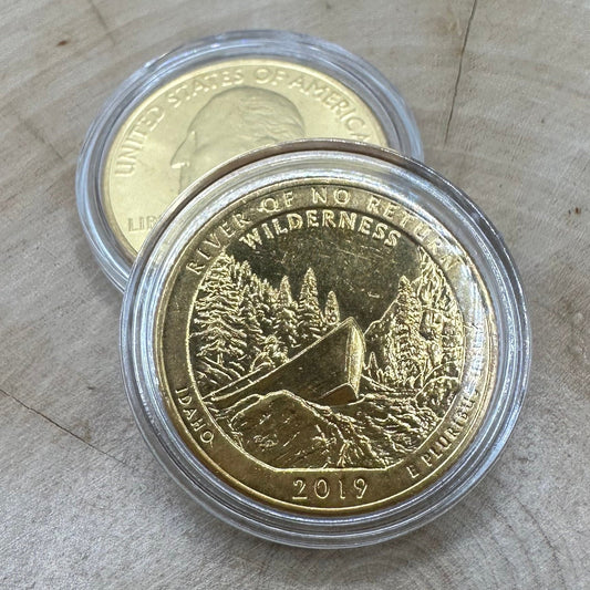 U.S. River of No Return Wilderness Quarter 24k Gold Plated Coin in a plastic case on a light wood round on top of the back of a U.S. River of No Return Wilderness Quarter 24k Gold Plated Coin in a plastic case.
- Mountainstruck Coin Jewelry
