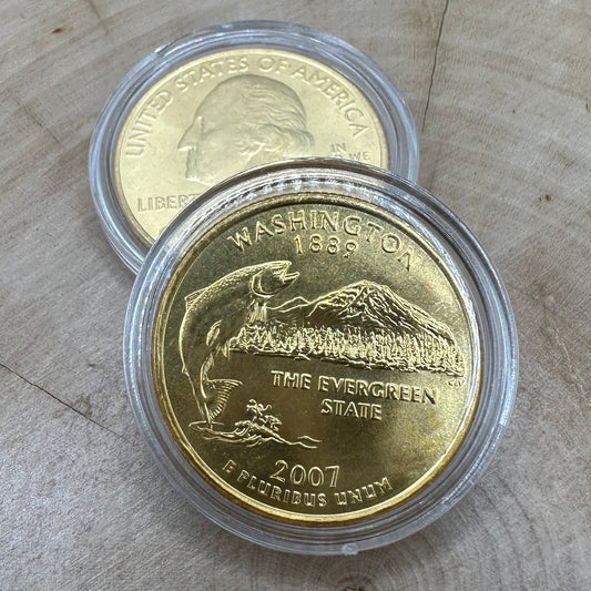 U.S. Washington Quarter 24k Gold Plated Coin in a plastic case on a light wood round on top of the back of a U.S. Washington Quarter 24k Gold Plated Coin in a plastic case.
- Mountainstruck Coin Jewelry