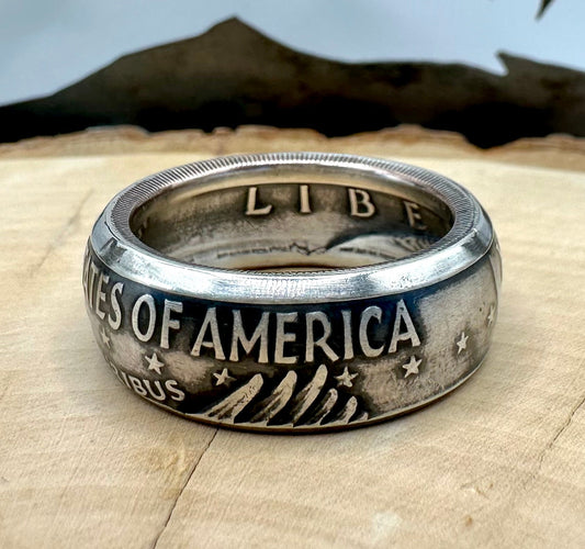 U.S. Eisenhower One Dollar 40% Silver Coin Ring on a light wood round with a metal mountain background. - Mountainstruck Coin Jewelry
