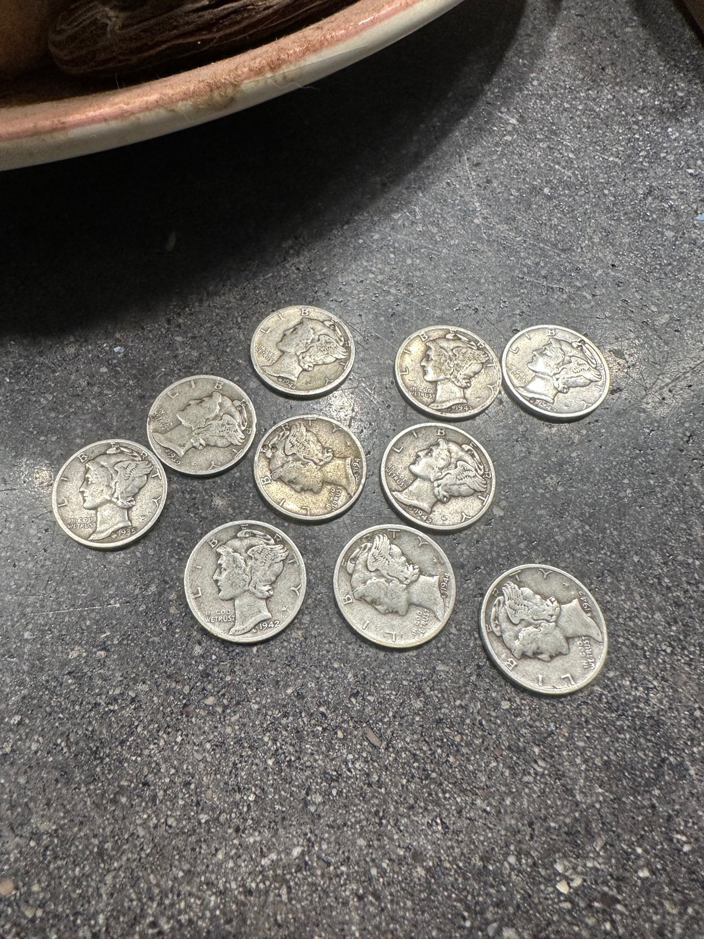 Mercury Silver Dime Coins on a concrete surface