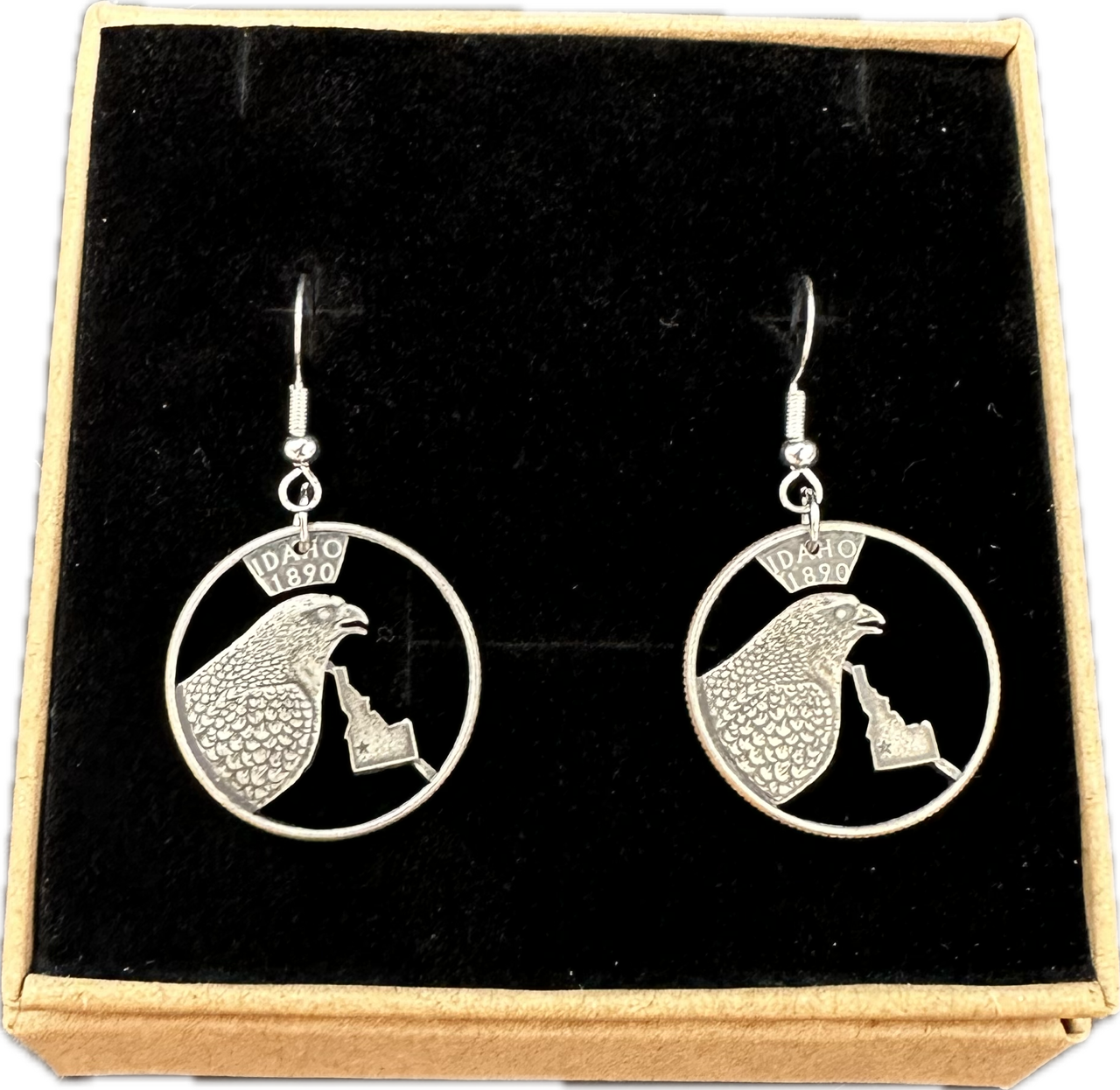 Idahome State Quarter Hand Cut Coin Earrings in a brown kraft box on a black velvet background.
