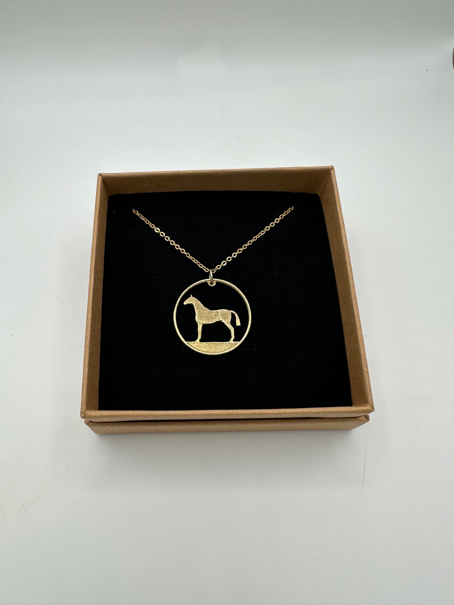 Horse Ireland 20 Pence Hand Cut Coin Necklace in a brown kraft box on a black velvet background.