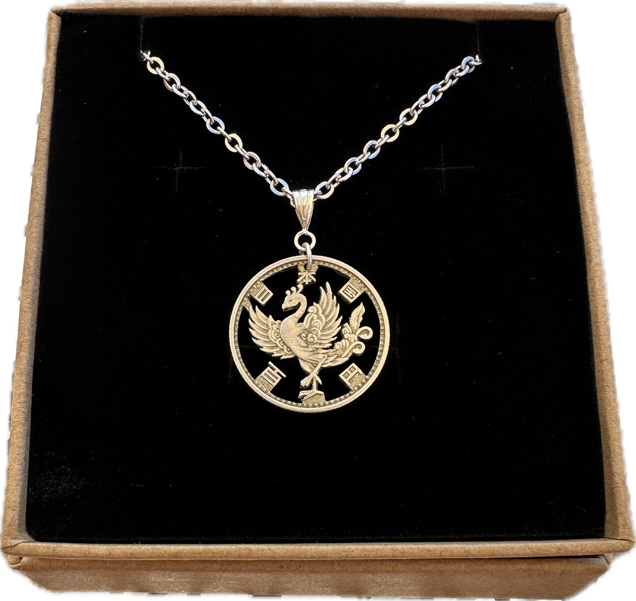 Phoenix Japan 100 Yen Silver Hand Cut Coin Necklace in a brown kraft box on a black velvet background.