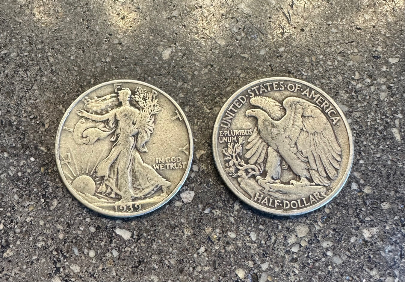 U.S. Walking Liberty Silver Coin on a concrete background. Front face of coin on the left in the picture and back side of the coin on the right.