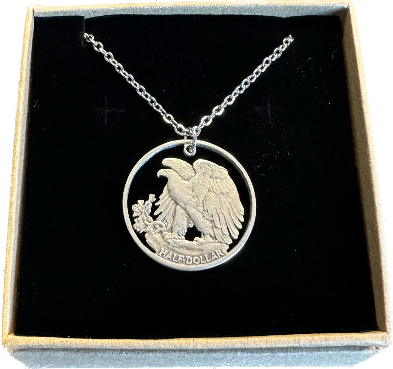 U.S. Walking Liberty Silver Hand Cut Coin Necklace (Eagle) with a stainless chain in a brown kraft box on a black velvet background.