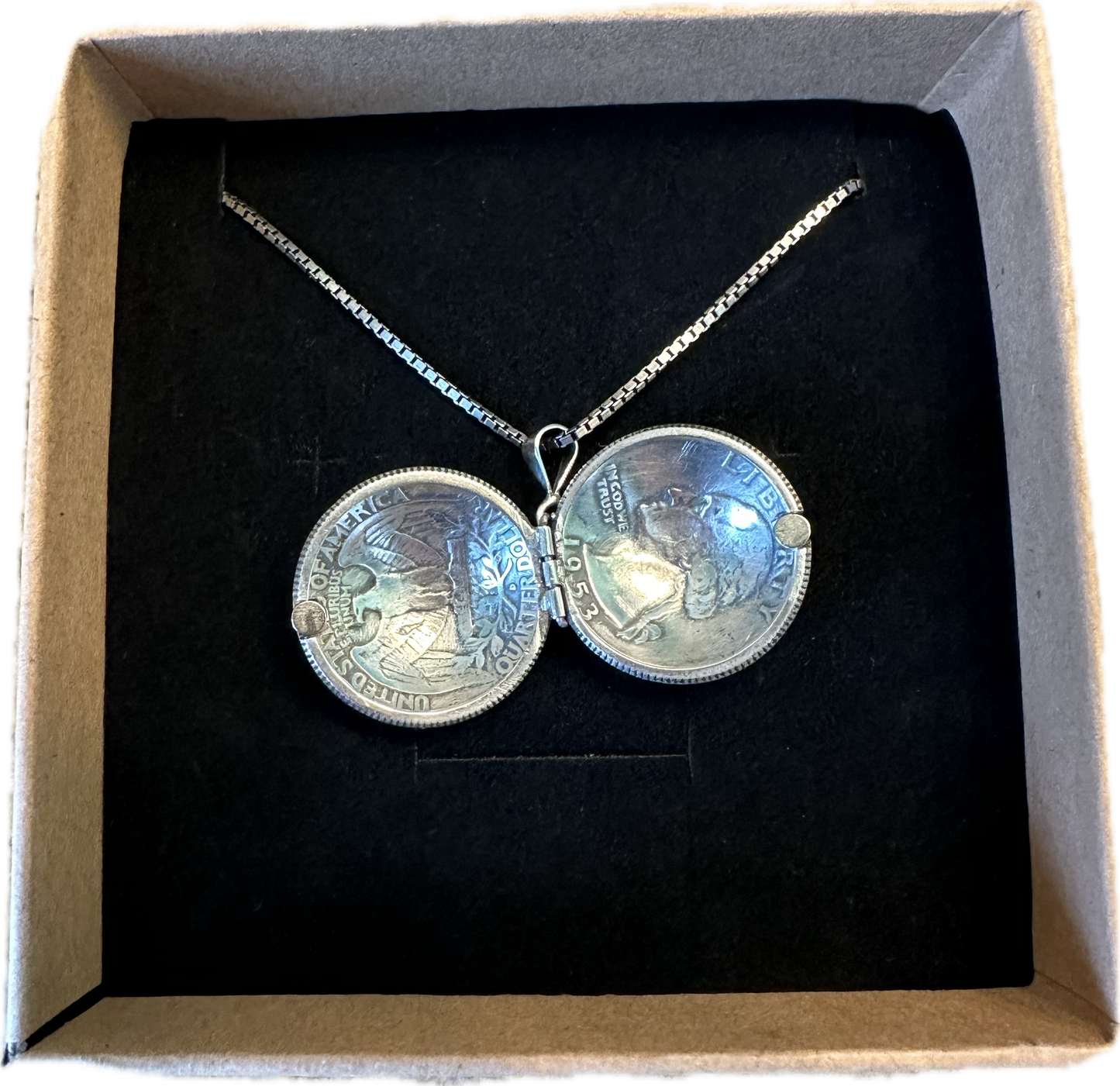 U.S. Silver Quarter Hand Crafted Coin Locket Necklace open in a brown kraft box on a black velvet background.