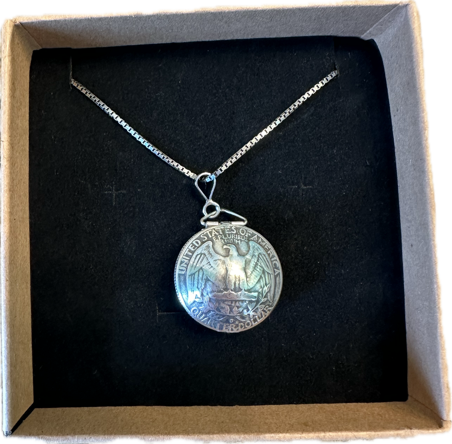 U.S. Silver Quarter Hand Crafted Coin Locket Necklace back side in a brown kraft box on a black velvet background.