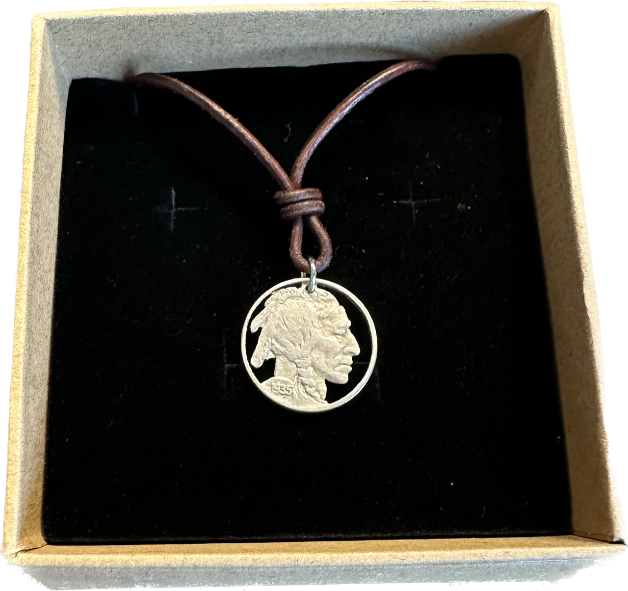 U.S. Buffalo Nickel (Front) Coin Necklace with a leather cord in brown kraft box on black velvet background.