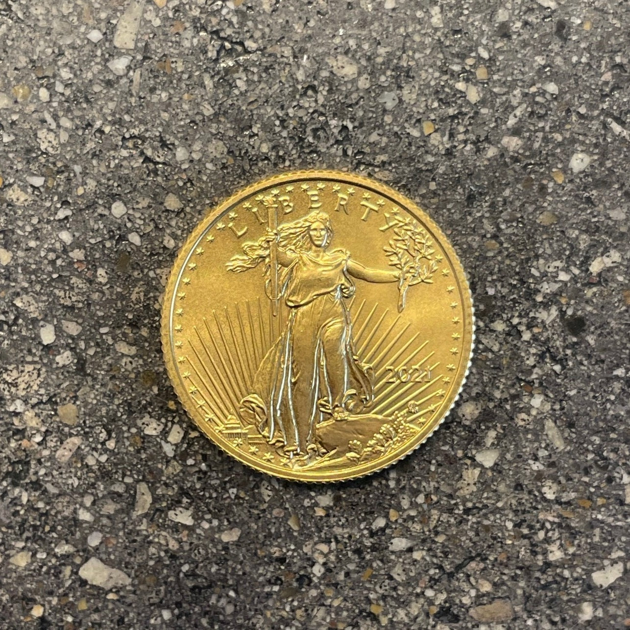 U.S. Gold Eagle 1/4 oz Fine Gold Coin back on a concrete background.