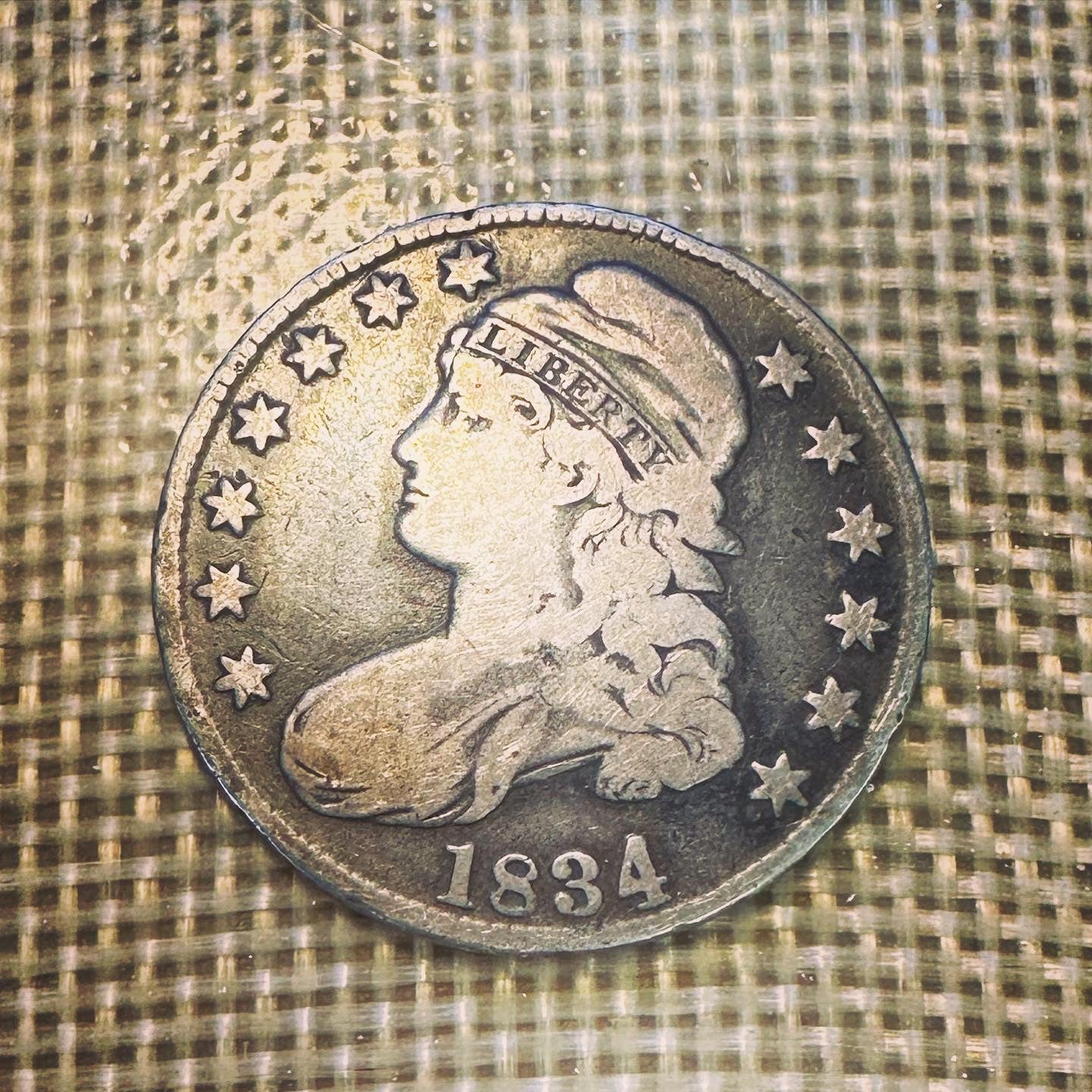 (Rare) Capped Bust Liberty Silver Half Dollar front of coin on woven background.