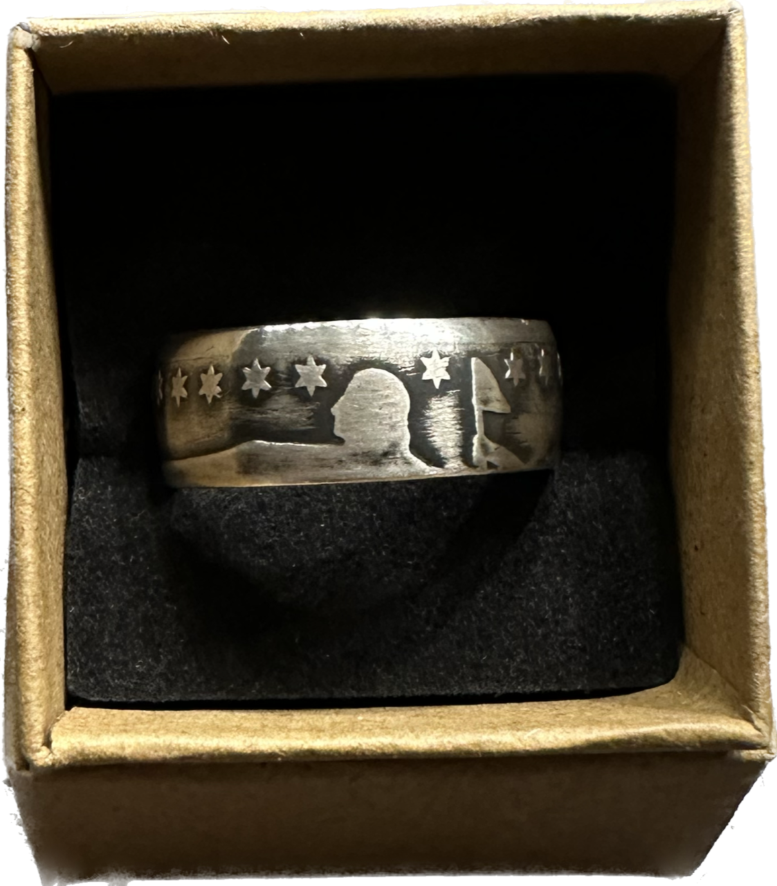 Seated Liberty Silver Half Dollar Coin Ring (patina) in a brown kraft box on a black velvet background.